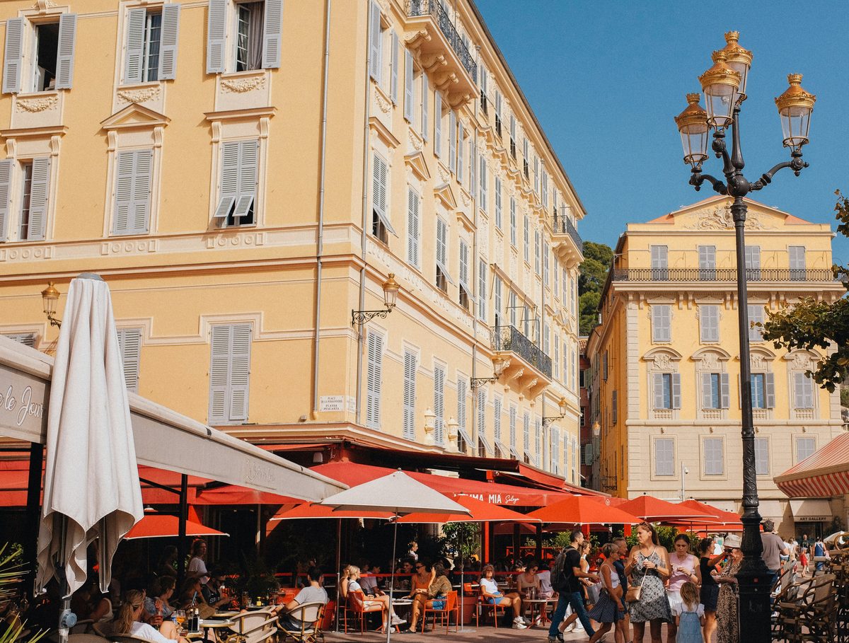 Busy restaurant terraces on Cours Saleya in Old Nice, colourful Mediterranean buildings